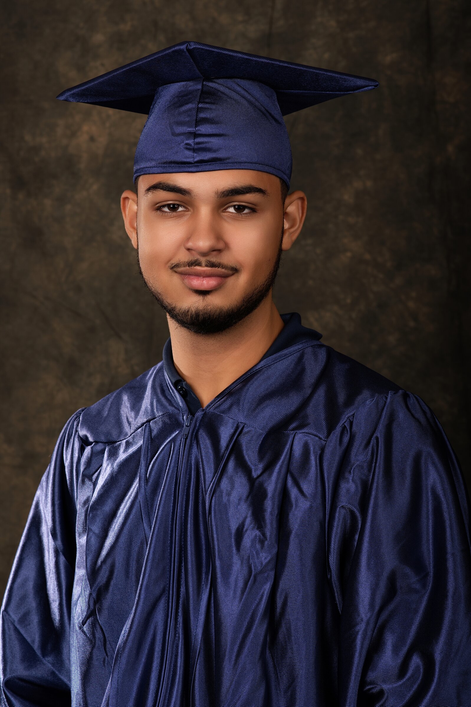 Cap and gown senior portrait of a graduate on a studio backdrop